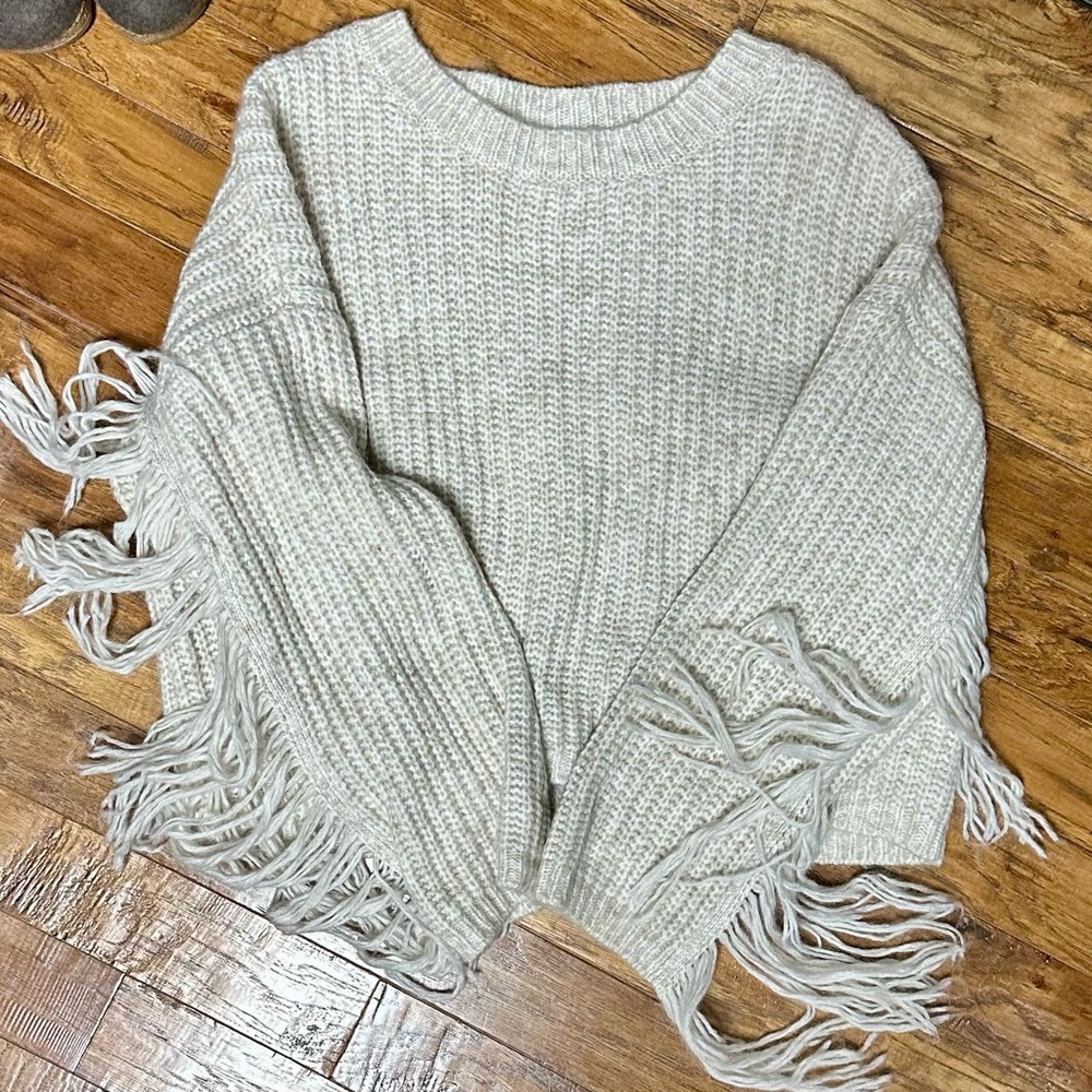 Cream sweater with fringe on sleeves and on back of sweater. 
Great condition.